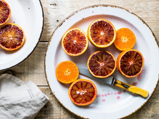 Половинки апельсина на тарелке с ножом