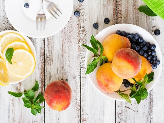 Персики на столе с лимоном и ягодами черники