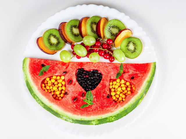 Кусок арбуза на тарелке с киви и ягодами 