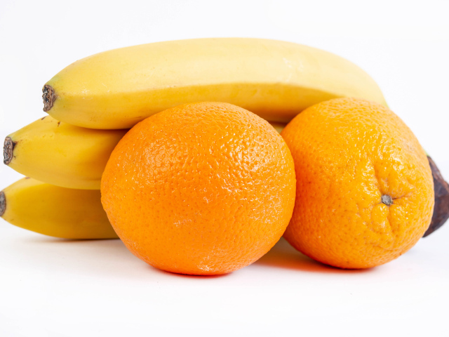 Спелые апельсины и бананы на белом фоне 