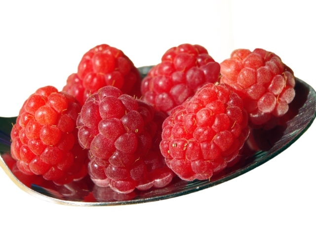 Спелая красная малина в ложке на белом фоне 