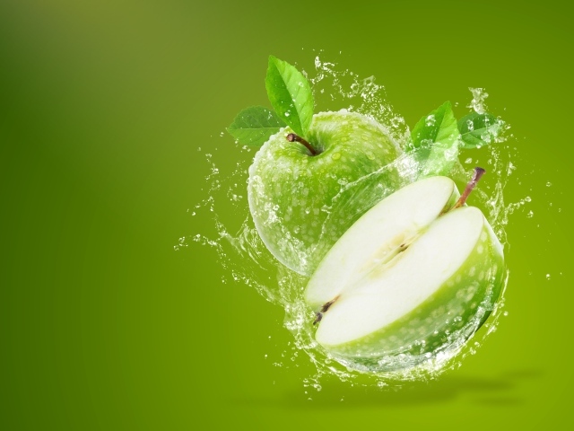 Два зеленых яблока в брызгах воды на зеленом фоне