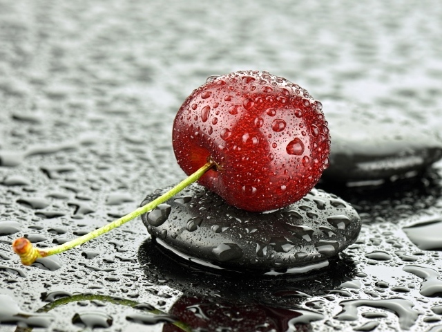 Мокрая черешня лежит на черном камне
