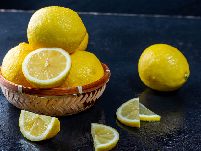 Мокрый лимон с кусочками на черном столе 