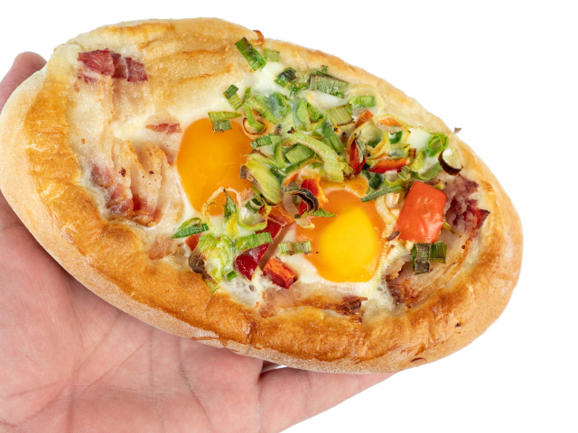 Вкусный свежий хачапури с яйцом и беконом в руке