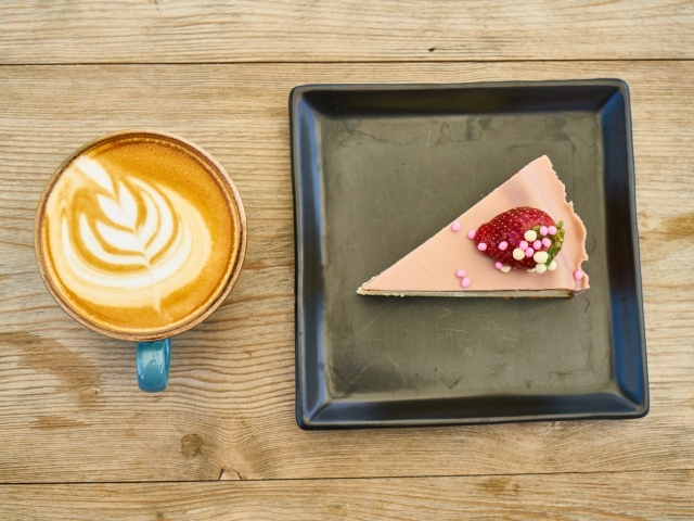 Кусок торта на черной тарелке с кофе