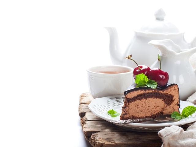 Кусок торта с ягодами черешни на столе с чаем