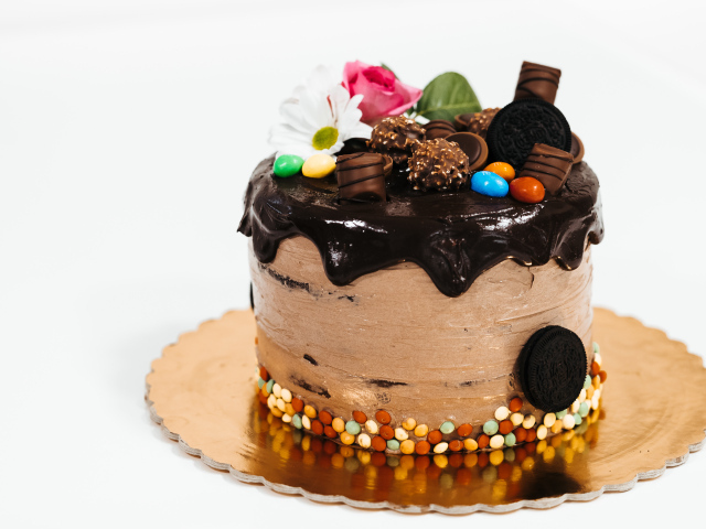Торт с кремом и шоколадом украшен сладостями