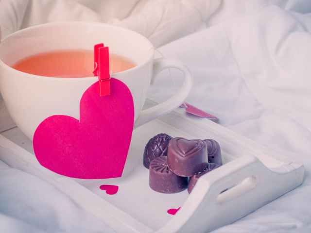 Чашка кофе с красным сердцем и шоколадными конфетами 