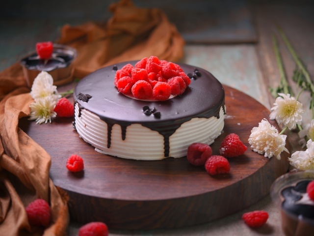 Вкусный торт с шоколадом и малиной на столе с цветами хризантемы 