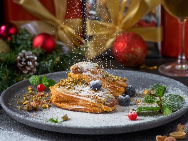 Вкусные сладкие эклеры с сахарной пудрой на блюде с ягодами 