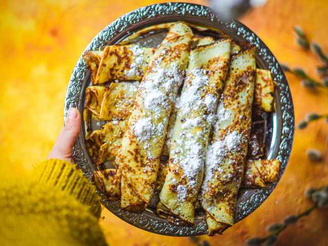 Вкусные тонкие блины с сахарной пудрой на блюде