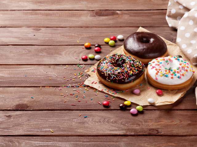 Пончики с глазурью на столе с конфетами на деревянном столе