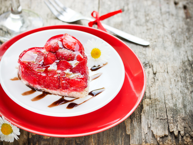 Пирожное с клубникой в форме сердца на тарелке с ромашками