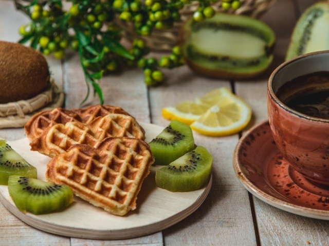Вафли в форме сердца на доске с киви и чашкой кофе