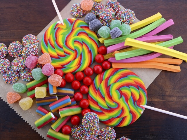 Разноцветные желейные конфеты, мармелад и леденцы на палочке на столе