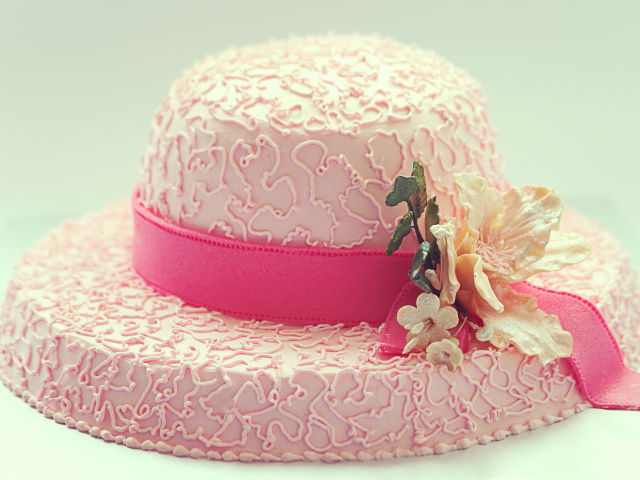 Розовый торт в виде шляпы на столе 
