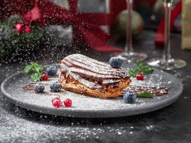 Вкусное пирожное на тарелке с сахарной пудрой и ягодами