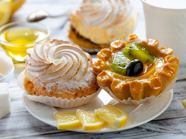 Вкусные аппетитные пирожные на тарелке с лимоном