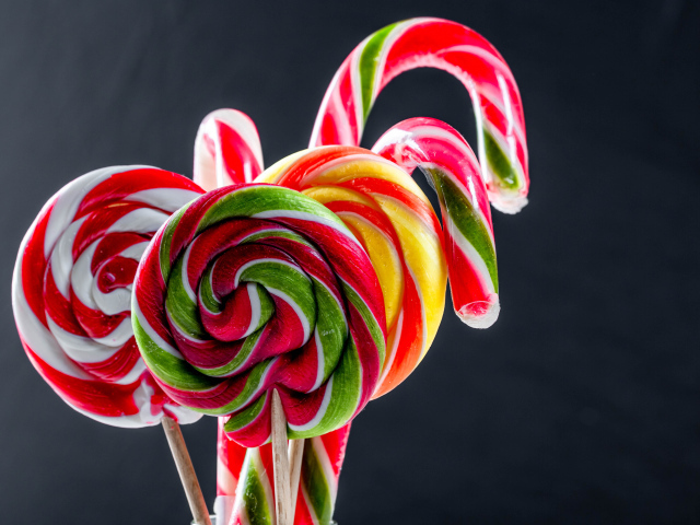 Вкусные разноцветные конфеты на палочке на сером фоне