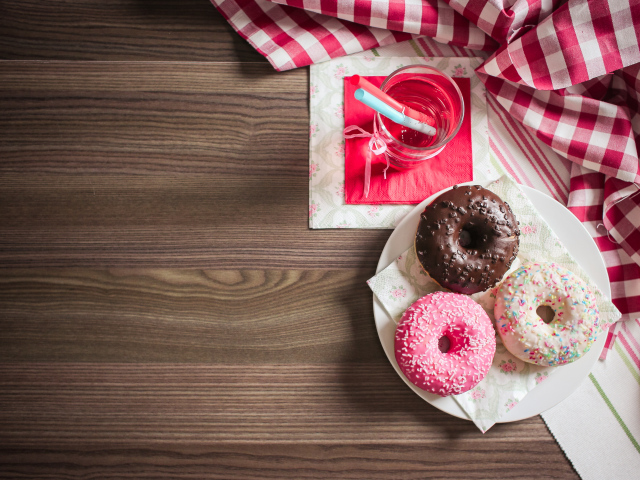 Три сладких пончика с глазурью на столе с лимонадом