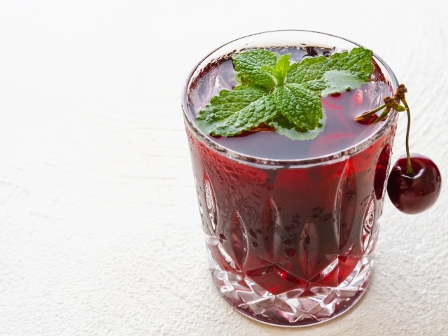 Стакан вишневого сока с мятой на белом фоне