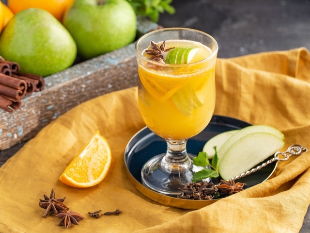 Стакан лимонада на столе с яблоками и корицей 