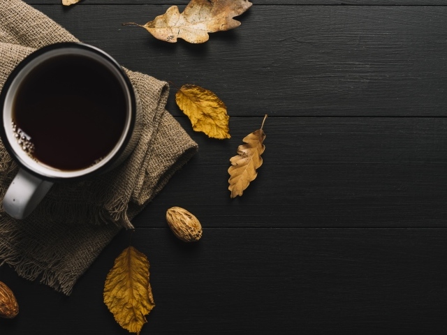 Чашка кофе на черном столе с листьями