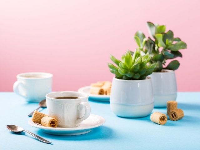 Чашка кофе на блюдце с вафлями на столе с цветами