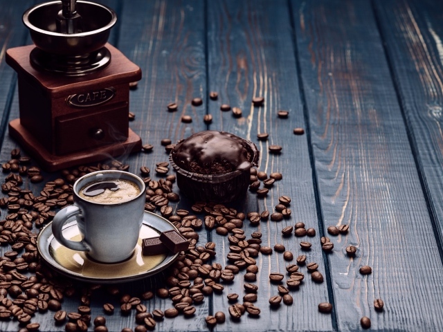 Чашка кофе на столе с шоколадным кексом и кофемолкой
