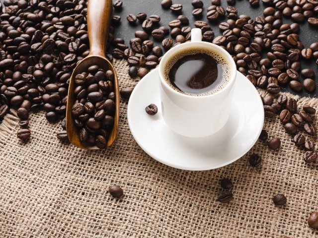 Чашка кофе на столе с зернами 