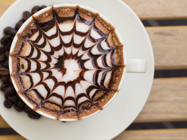 Чашка кофе с рисунком на пене на столе