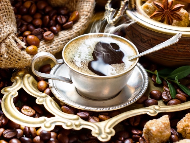 Чашка горячего вкусного кофе на столе с зернами