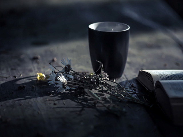 Чашка чая на столе с ромашками и книгой 