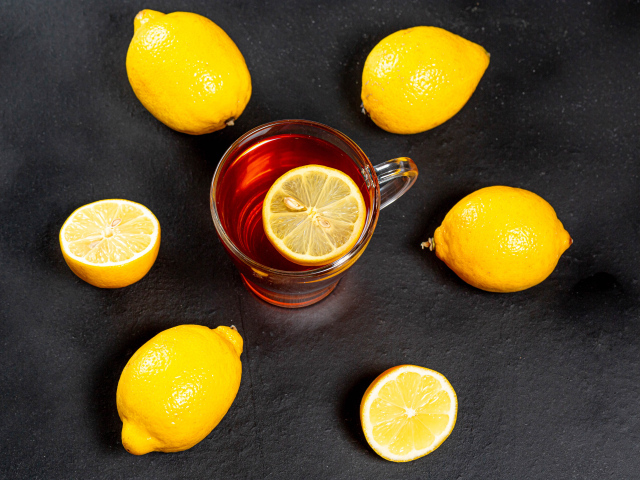 Стеклянная чашка чая с лимоном на сером столе 