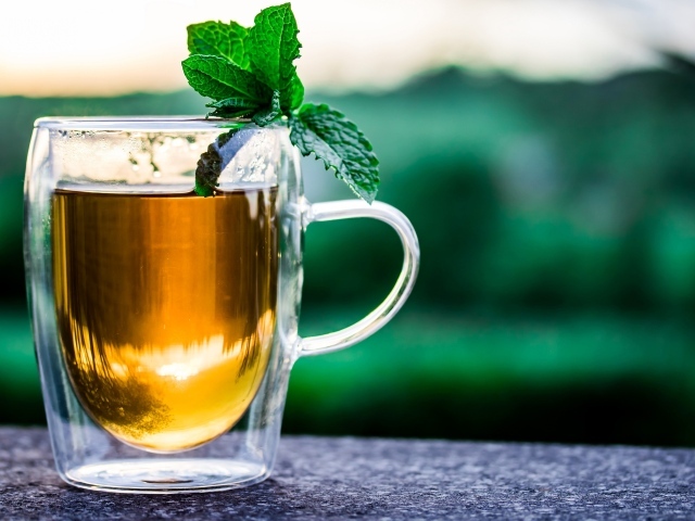 Стеклянная чашка чая с мятой на столе 