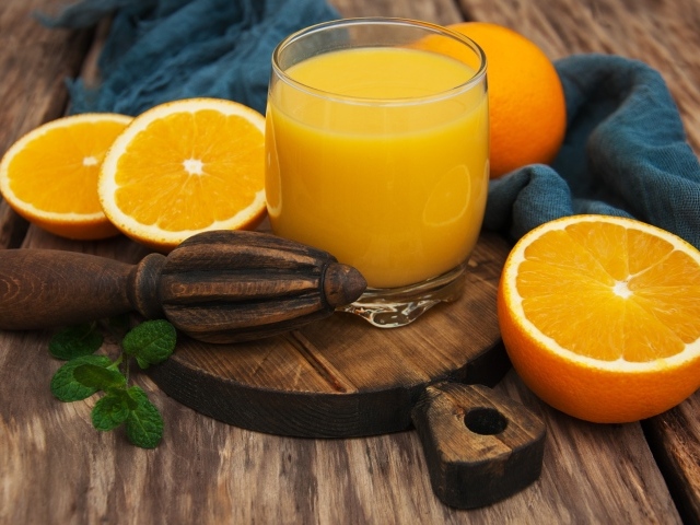Стакан сока на доске с апельсинами 