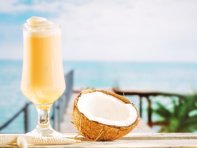 Стакан с коктейлем на столе с кокосом 