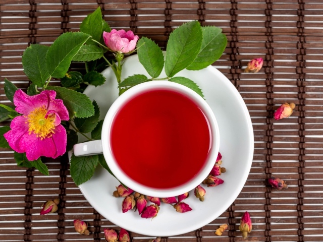 Красный чай с шиповника на столе с цветами