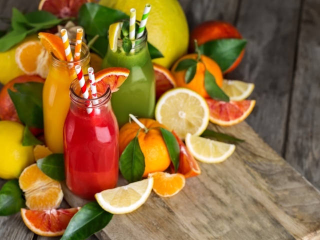 Три бутылки с соком на столе со свежими фруктами