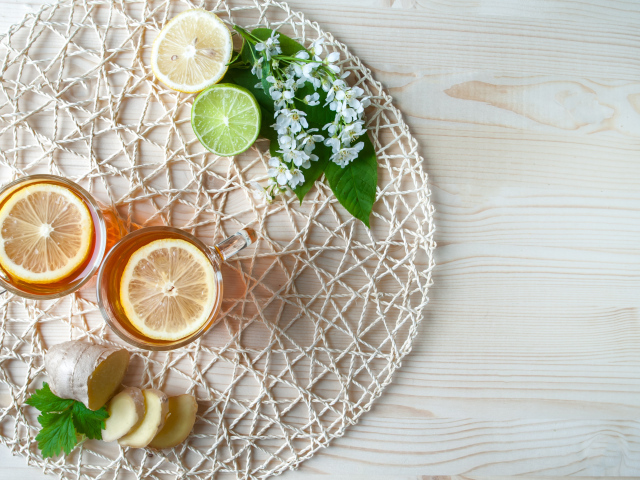 Две чашки чая с лимоном на плетеной подставке 