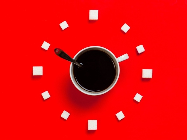 Белая чашка кофе на красном фоне с кубиками сахара 