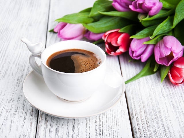 Белая чашка кофе на столе с букетом разноцветных тюльпанов 