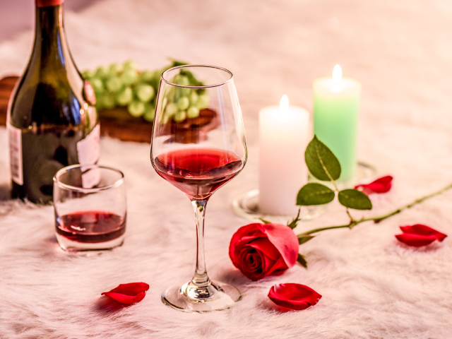 Вино на кровати с розой, виноградом и зажженными свечами