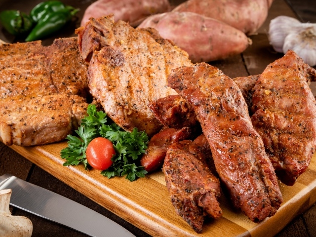 Аппетитное запеченное мясо на столе с чесноком и картофелем