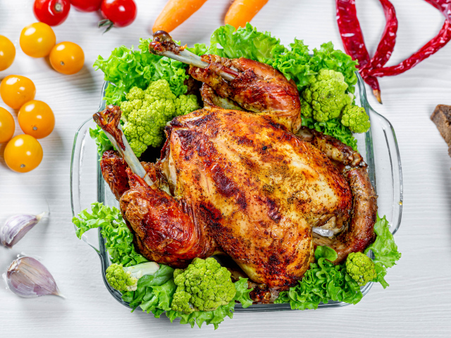 Запеченная курица с брокколи и листьями салата на столе с овощами