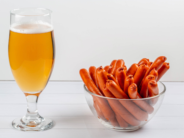 Вкусные сосиски на столе с бокалом пива