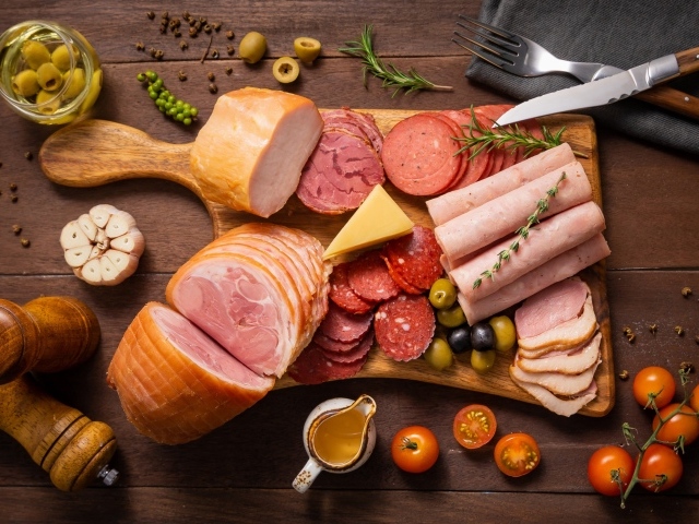 Колбасы и мясные продукты на доске со специями