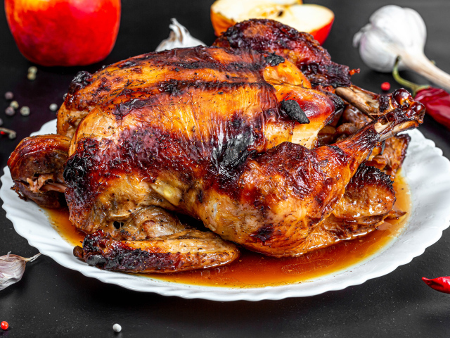 Вкусная запеченная курица на белой тарелке на столе с овощами