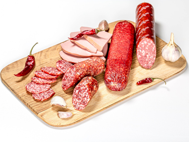Вкусная колбаса с красным перцем и чесноком на доске на белом фоне